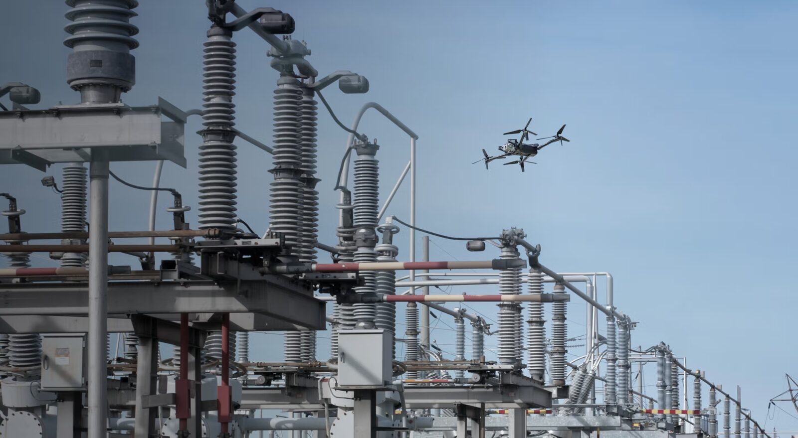 Inspection drone flying close to substation insulators